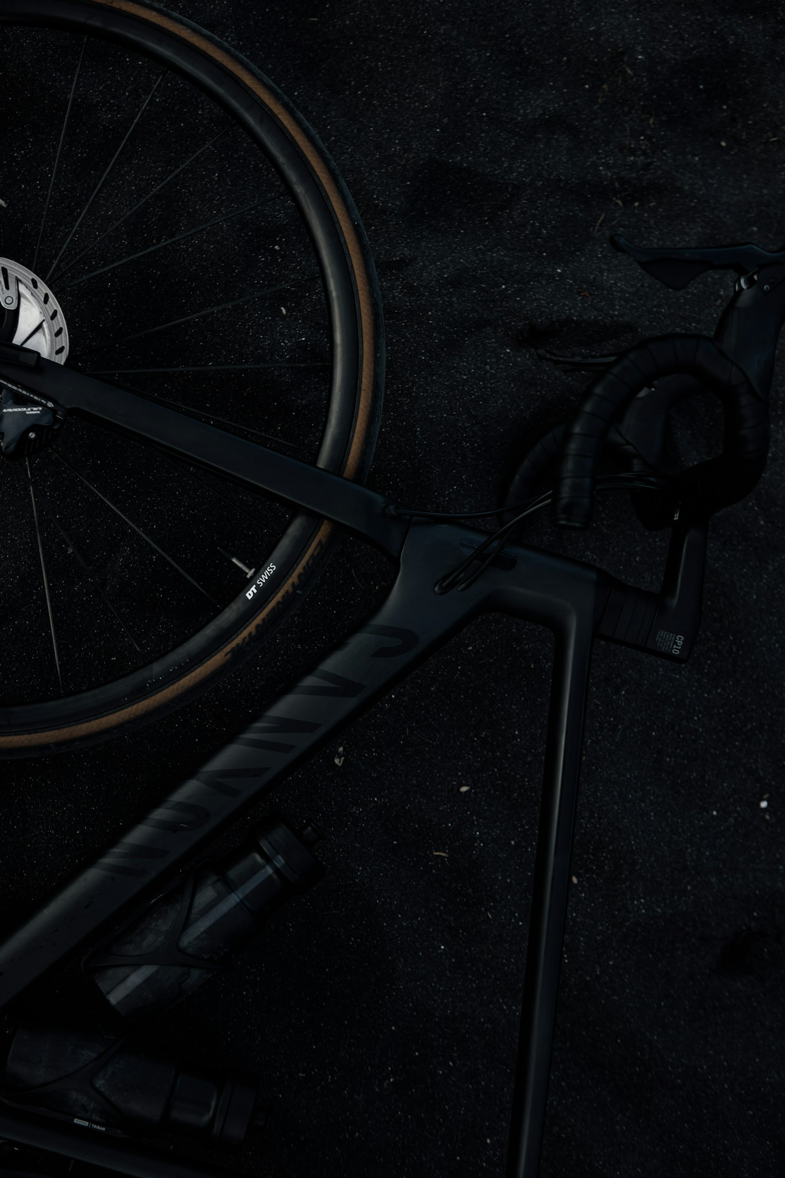 Schwarzes Airstreeem Carbon-Rennrad, top-down auf dunklem Asphalt